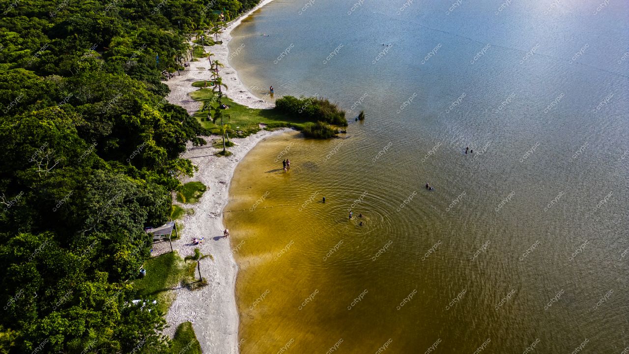 Morro das Pedras e Lagoa do Peri em Florianópolis com vegetação intensa e pessoas aproveitando a lagoa sob luz natural
