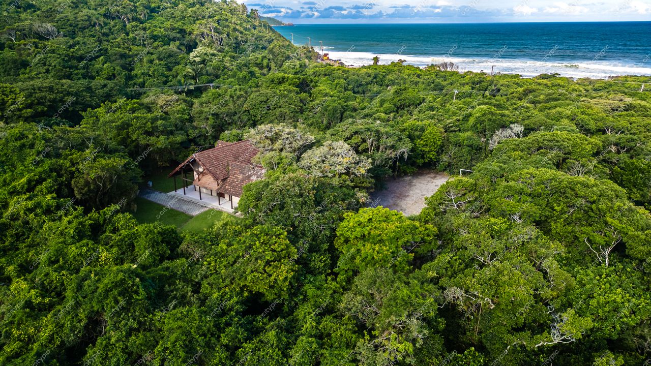 Morro das Pedras e Lagoa do Peri em Florianópolis com casa rústica, vegetação densa e costa rochosa ao fundo
