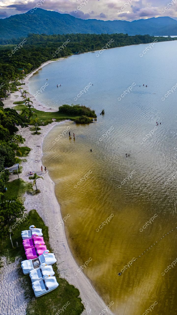 Morro das Pedras e Lagoa do Peri em Florianópolis com pedalinhos brancos e rosas na areia clara e vegetação ao redor