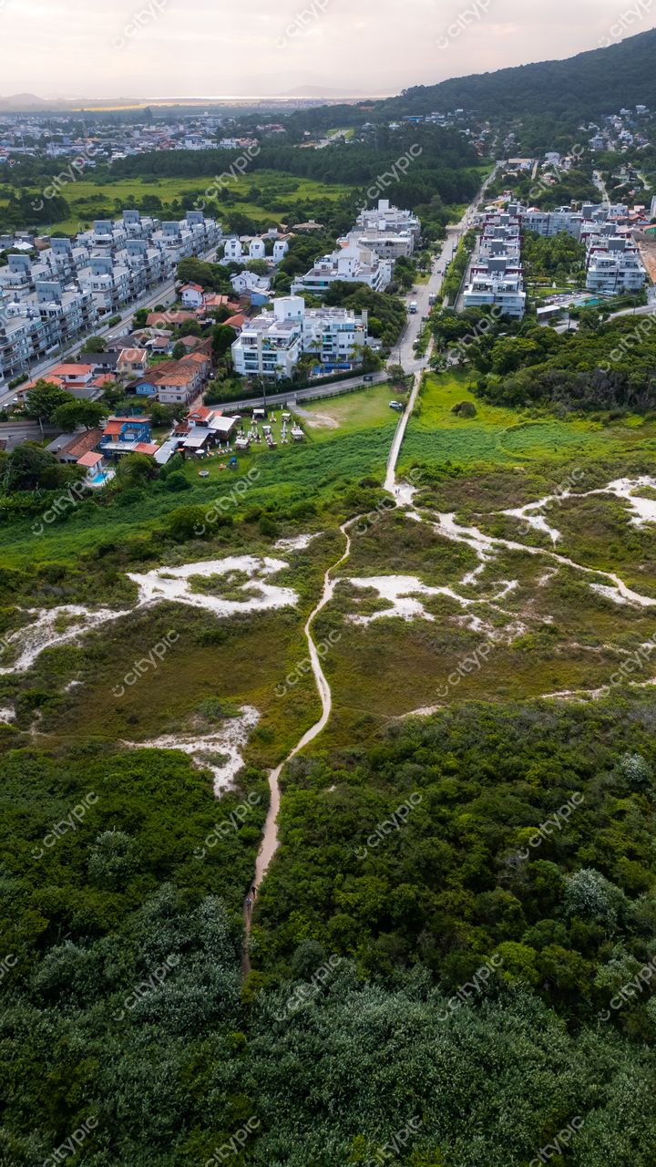 Campeche em Florianópolis com vista aérea do urbanismo, vegetação densa e relevo montanhoso ao entardecer