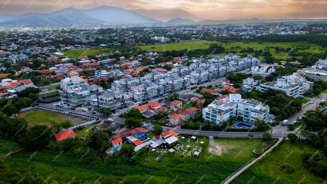 Campeche em Florianópolis com vista aérea destacando telhados vermelhos e montanhas ao fundo no final da tarde