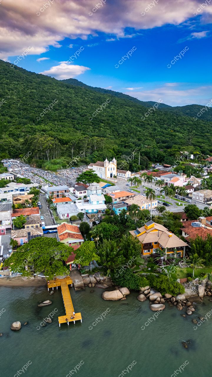 Ribeirão da Ilha em Florianópolis com vista aérea de telhados coloridos, vegetação densa e céu azul claro