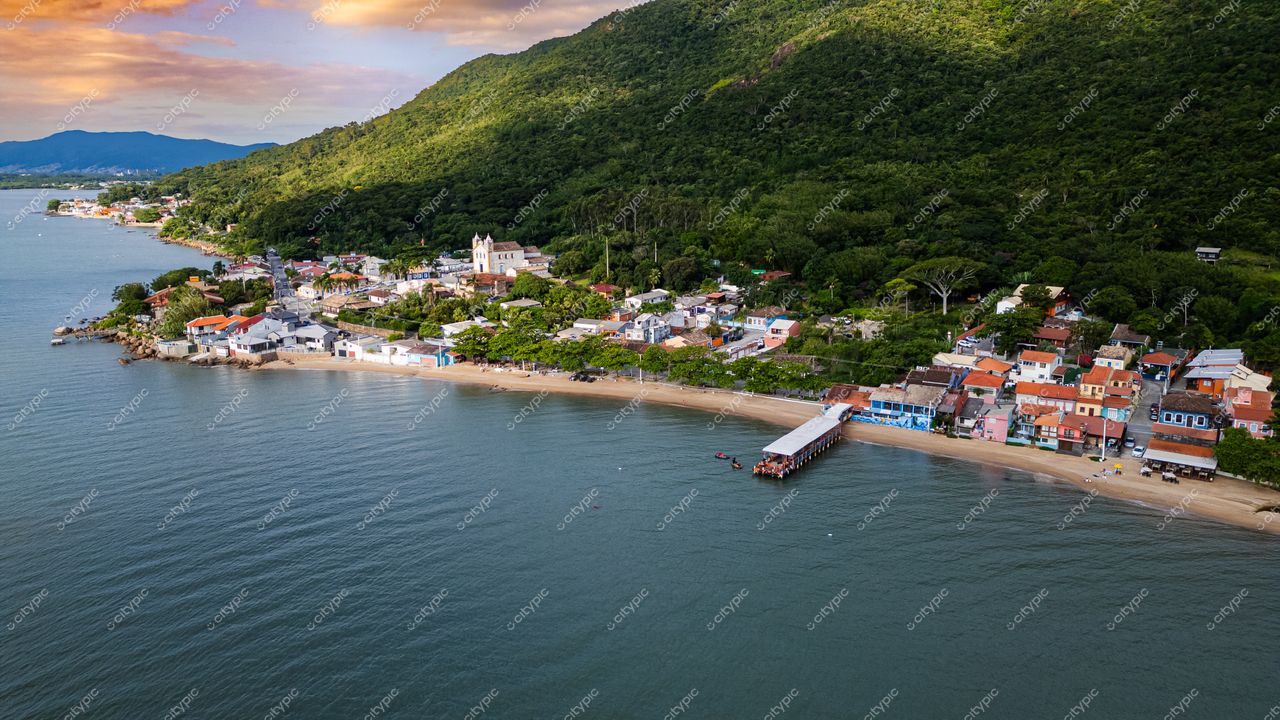 Ribeirão da Ilha em Florianópolis ao entardecer com casas coloridas, vegetação densa e montanha ao fundo