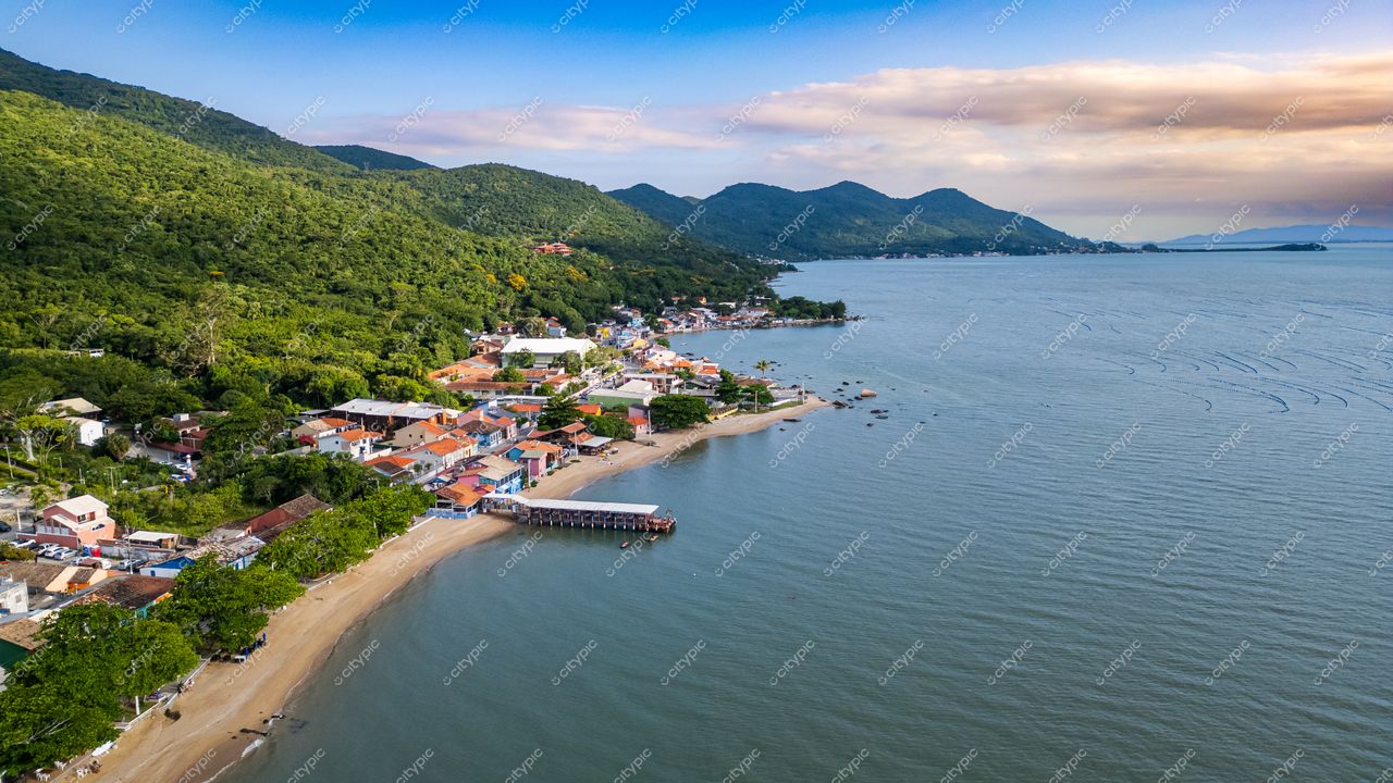 Ribeirão da Ilha em Florianópolis com casas coloridas, água tranquila e relevo montanhoso ao entardecer