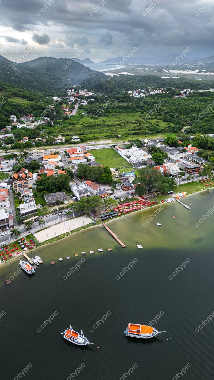 Rendeiras em Florianópolis com vista aérea da costa tranquila, barcos ancorados e vegetação verde intensa ao fundo