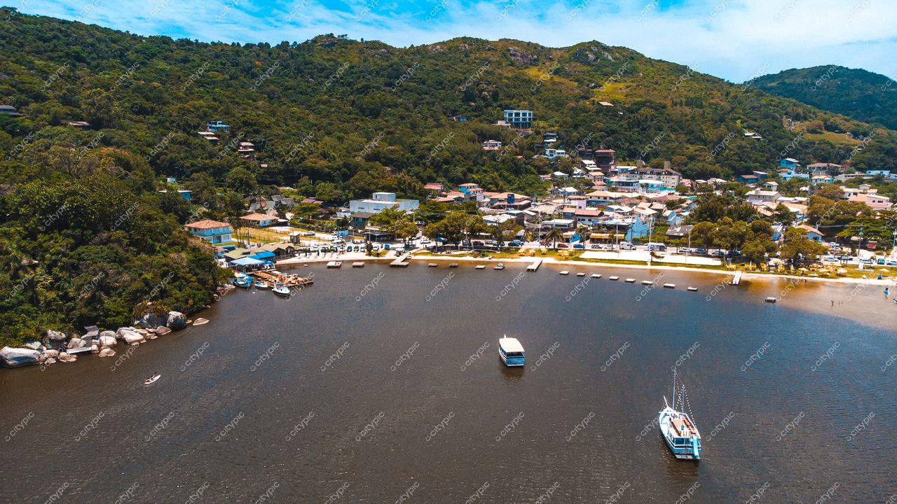 Florianópolis, Santa Catarina, vista aérea de enseada tranquila com vegetação densa e casas coloridas à margem
