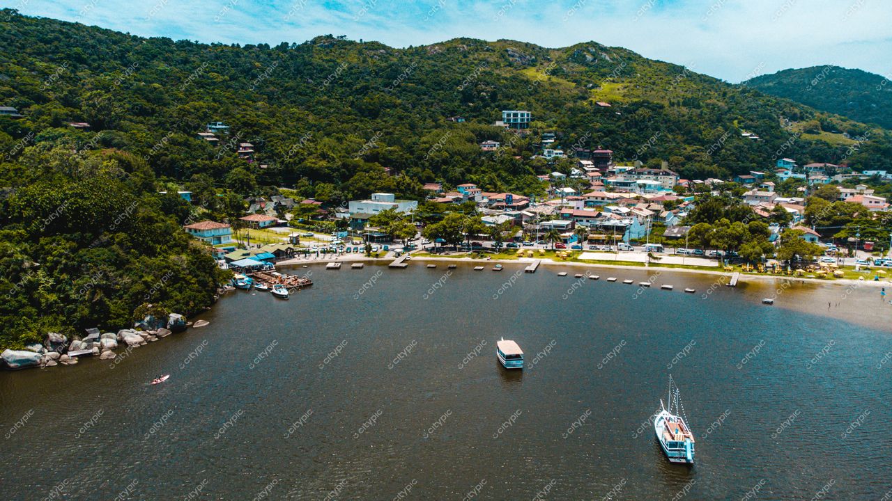 Florianópolis, Santa Catarina, vista panorâmica da baía com casas residenciais, vegetação densa e barcos ancorados em dia claro