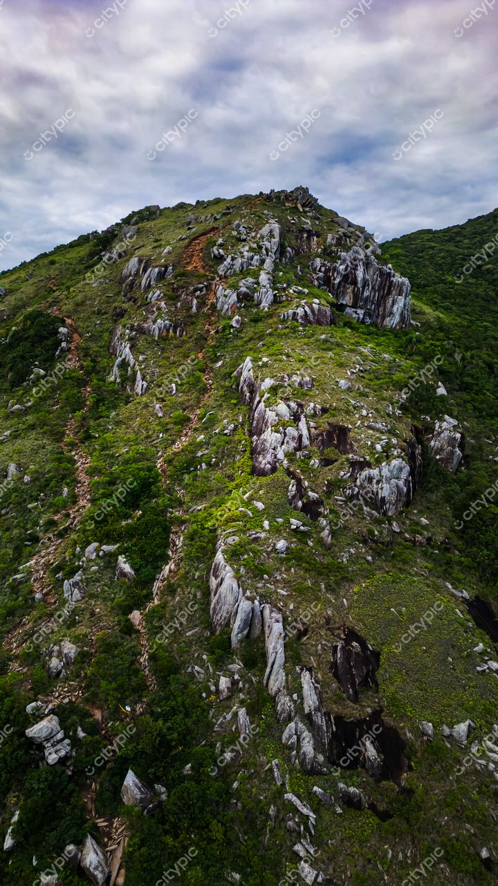 Lagoinha do Leste em Florianópolis com vista aérea de montanha, rochas expostas e vegetação verdejante sob céu nublado