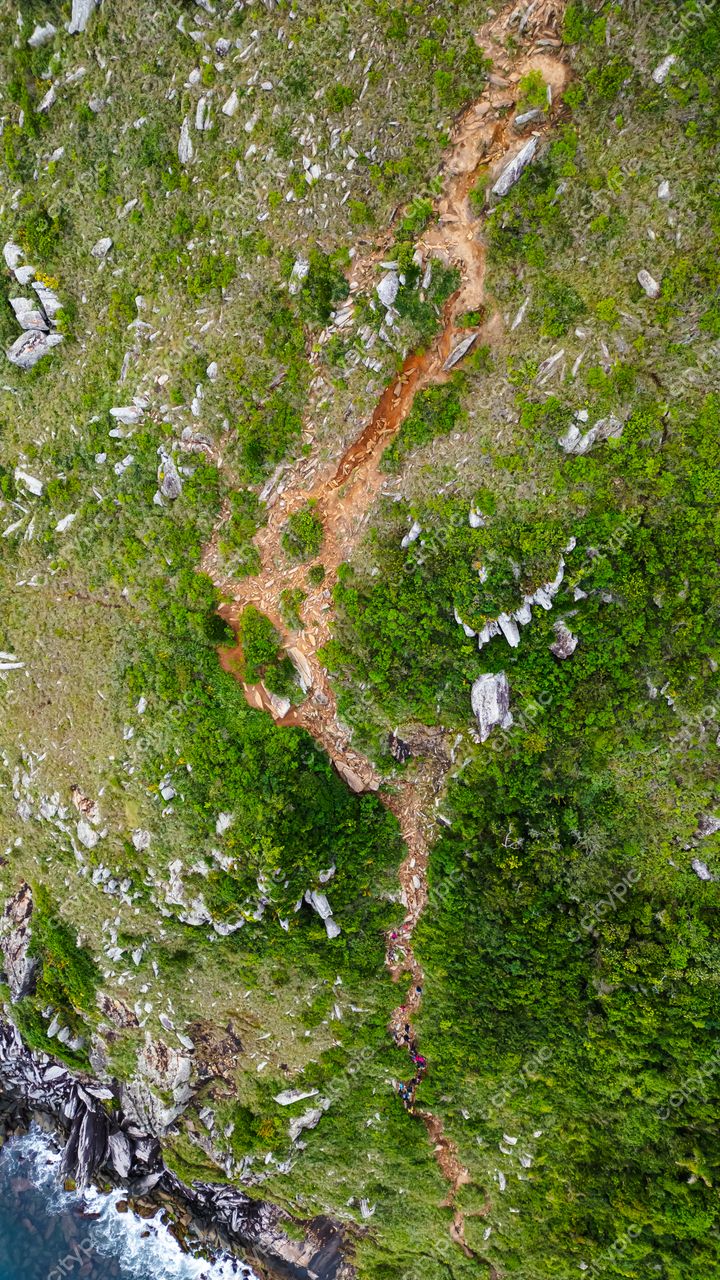 Lagoinha do Leste em Florianópolis com vista aérea da trilha avermelhada entre vegetação verde e rochas grandes