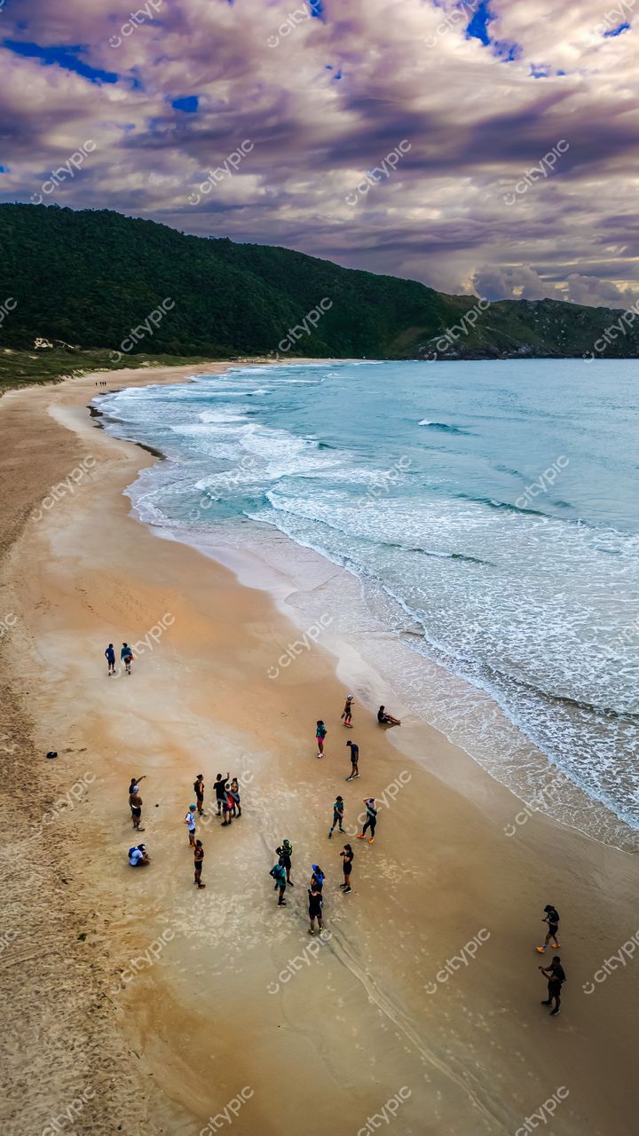 Lagoinha do Leste em Florianópolis com vista aérea de praia cheia e céu nublado, vegetação densa ao fundo