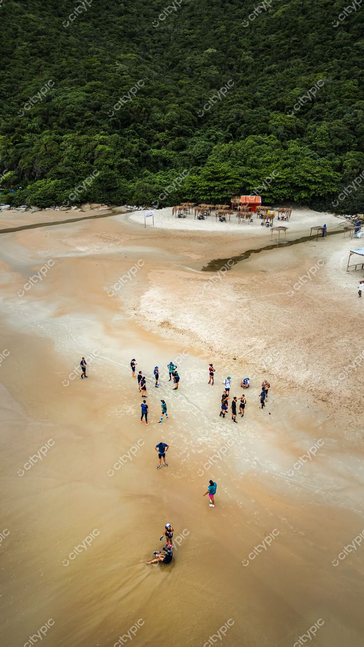 Lagoinha do Leste em Florianópolis com pessoas na areia molhada e vegetação densa ao fundo em dia nublado