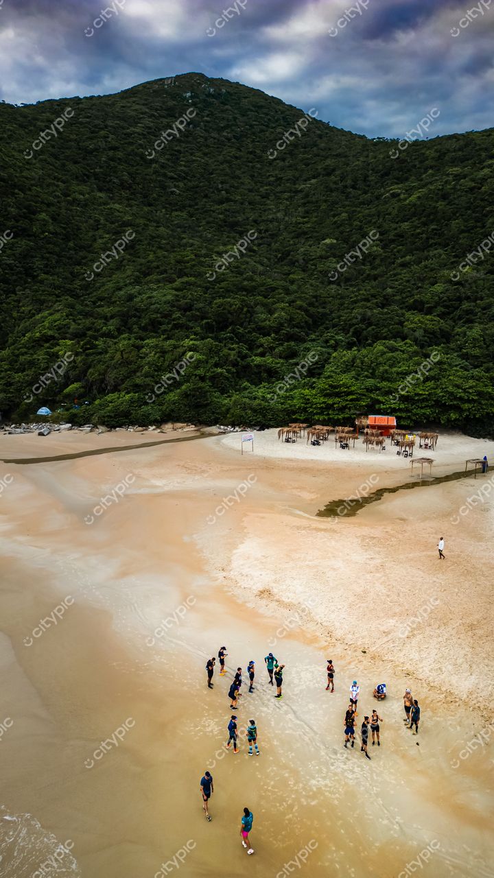 Lagoinha do Leste em Florianópolis com vista aérea, vegetação densa e pessoas na margem sob céu nublado