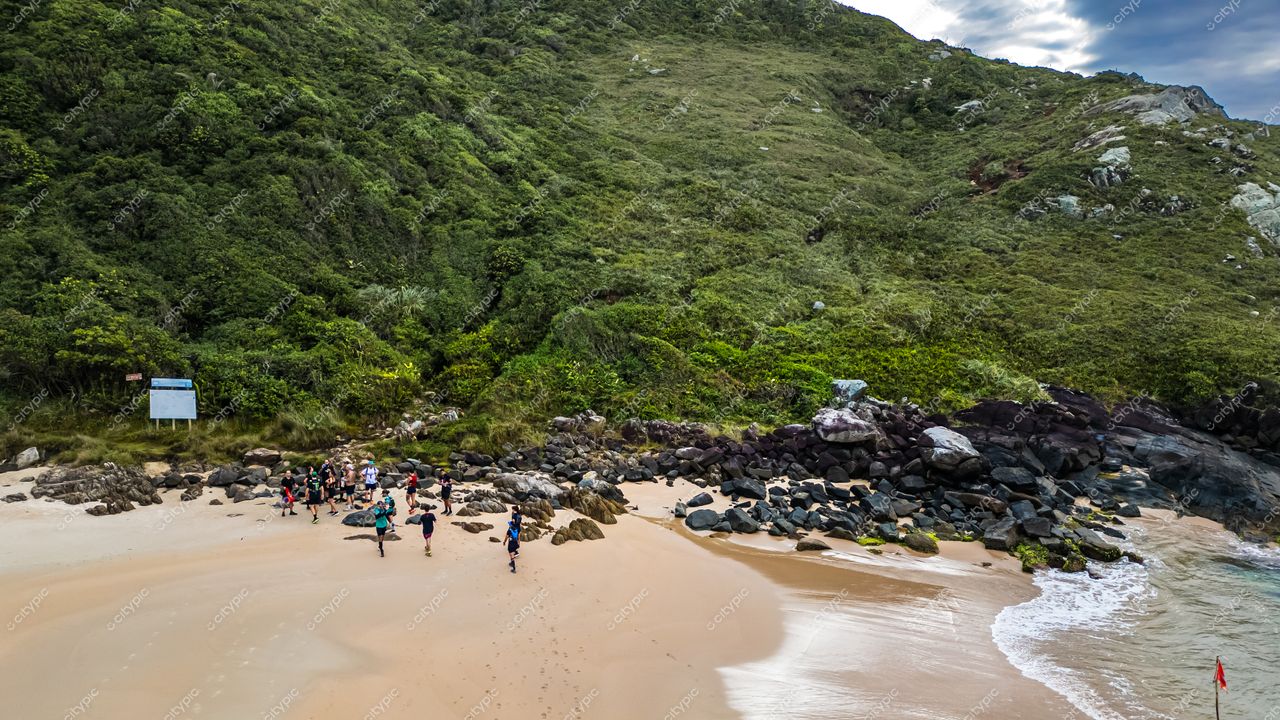 Lagoinha do Leste em Florianópolis com grupo de pessoas caminhando na areia clara sob céu parcialmente nublado