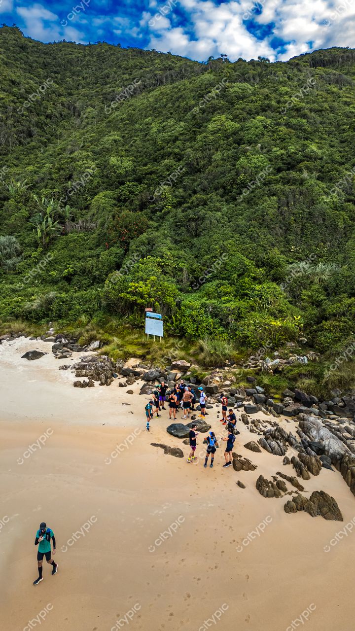 Lagoinha do Leste em Florianópolis com pessoas na areia e vegetação montanhosa ao fundo em dia parcialmente nublado