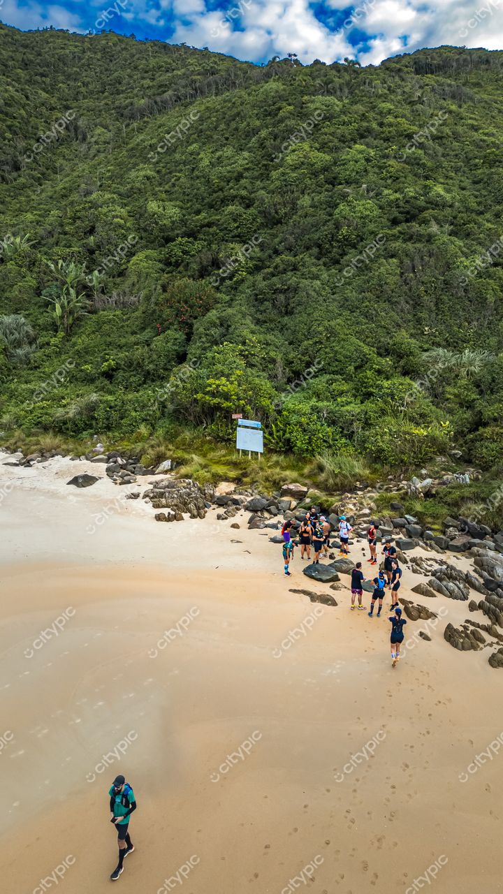 Lagoinha do Leste em Florianópolis com vegetação densa, rochas na praia e pessoas próximas às pedras durante o dia