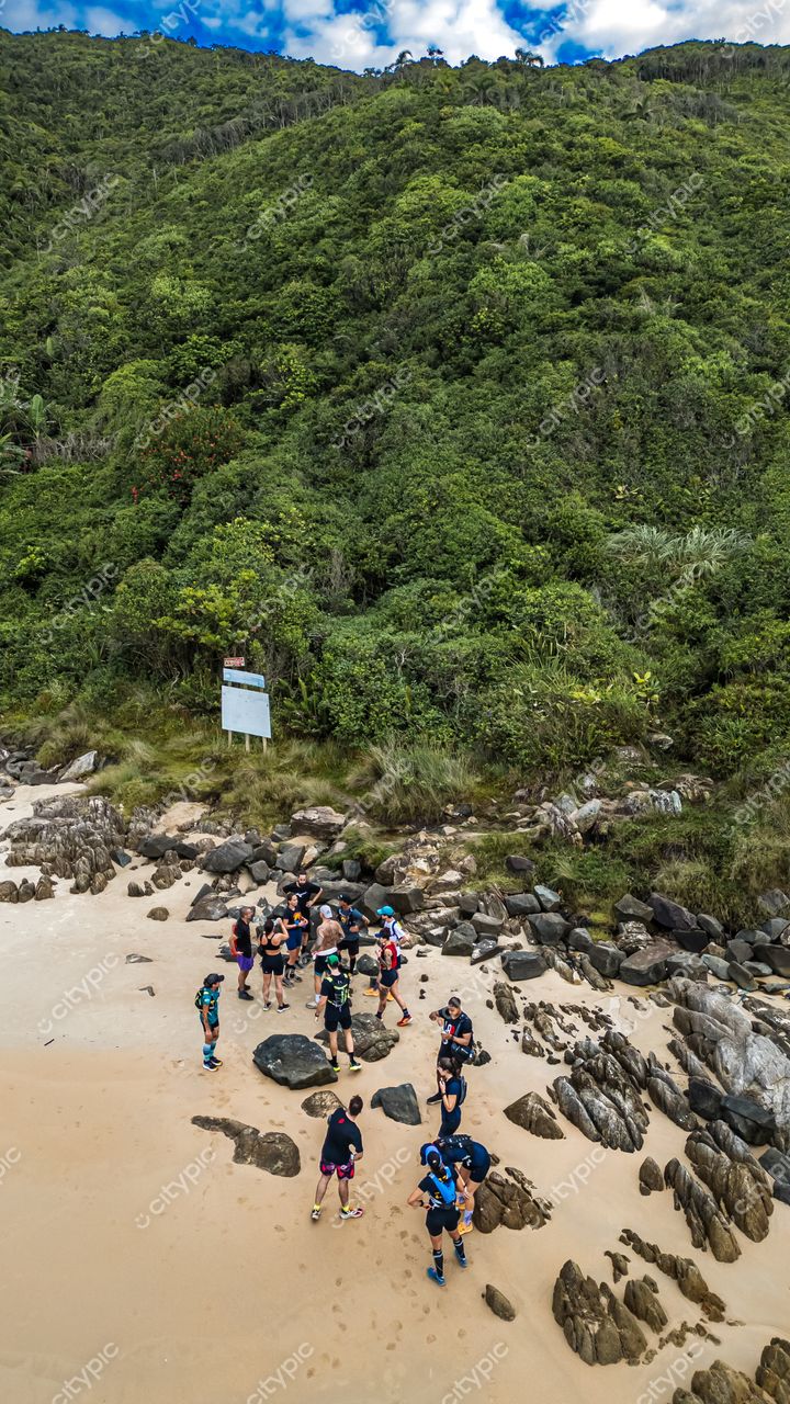 Lagoinha do Leste em Florianópolis com grupo de pessoas na praia e vegetação densa ao fundo em dia nublado
