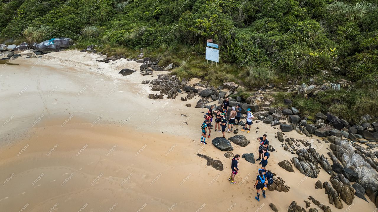 Lagoinha do Leste em Florianópolis com grupo de pessoas na praia sob céu nublado e vegetação densa