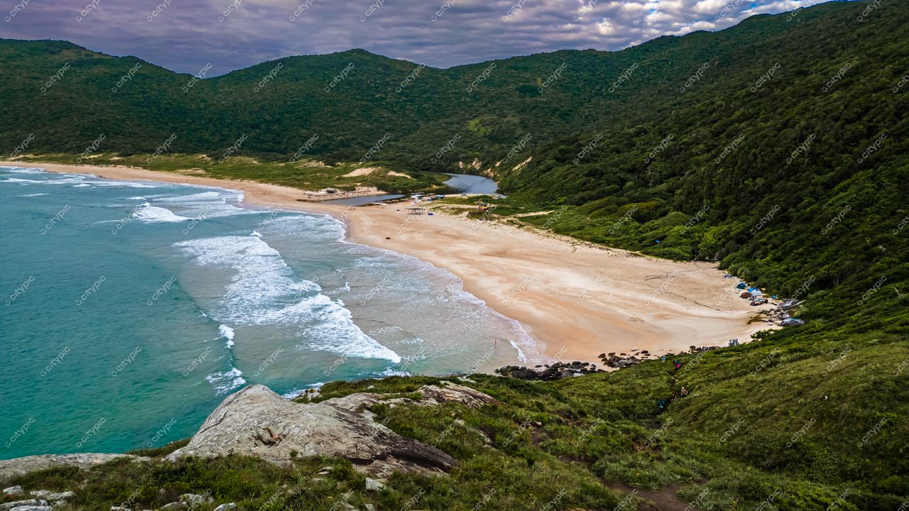 Lagoinha do Leste em Florianópolis com montanhas verdes, areia clara e lago refletindo vegetação em dia nublado