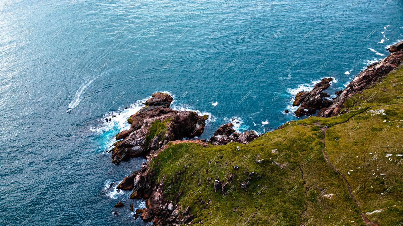 Lagoinha do Leste em Florianópolis com vista aérea da costa, rochas expostas e trilhas serpenteando pela vegetação verde
