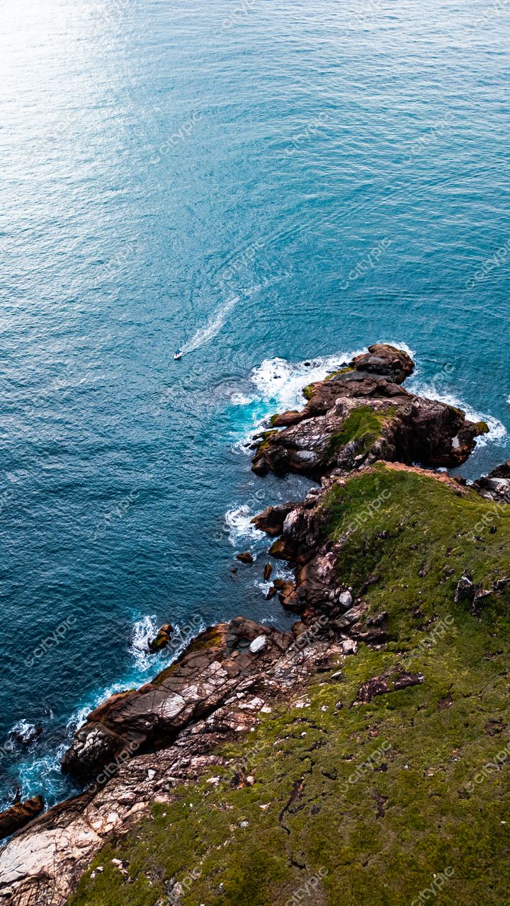 Lagoinha do Leste em Florianópolis com mar azul e verde, vegetação densa e barco ao longe em dia ensolarado