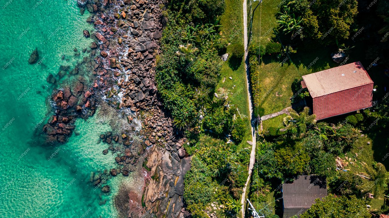 Lagoinha do Leste em Florianópolis com casa de telhado vermelho cercada por vegetação densa e costa rochosa
