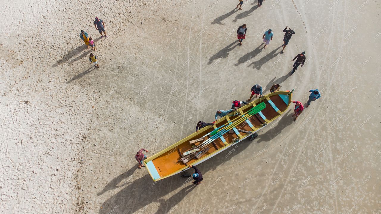 Florianópolis, Santa Catarina, entardecer na praia com grupo de pessoas ao redor de barco colorido e sombras na areia