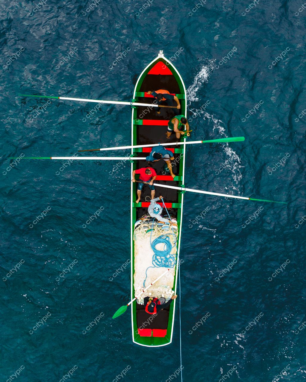 Florianópolis, Santa Catarina, canoa colorida com cinco homens remando em águas azuis sob luz natural suave