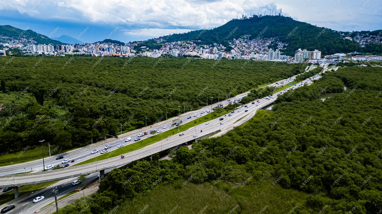 Hospital SOS Cárdio em Florianópolis com vista aérea mostrando vegetação densa e tráfego moderado sob céu nublado