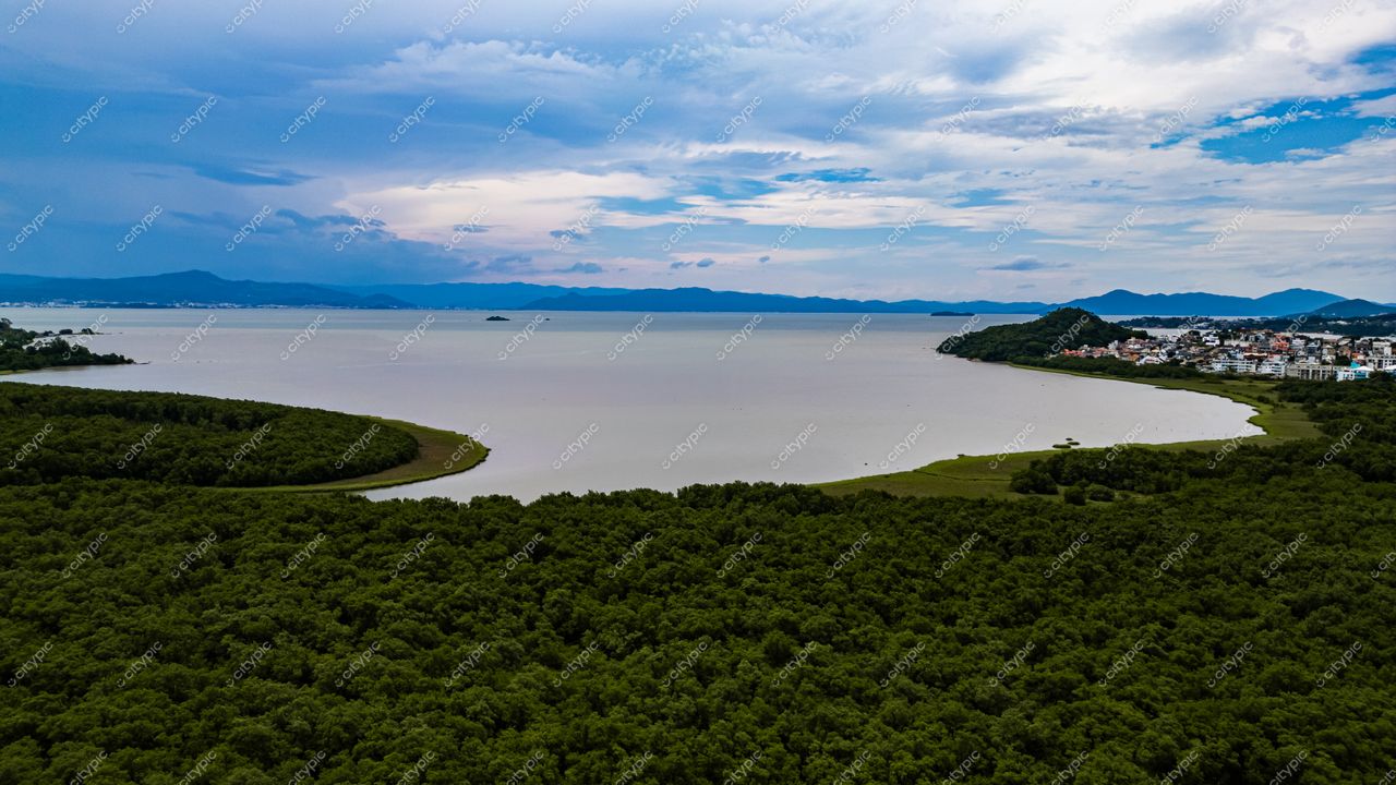 Hospital SOS Cárdio em Florianópolis com vista aérea da lagoa e vegetação densa ao entardecer com céu nublado