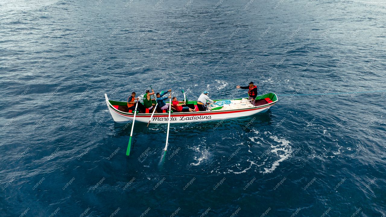 Florianópolis, Santa Catarina, canoa tradicional colorida com cinco pessoas remando em águas calmas sob céu claro