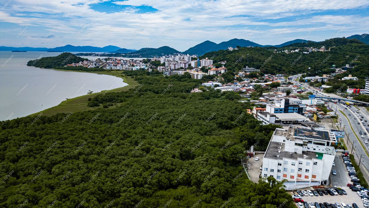 Hospital SOS Cárdio em Florianópolis com vista aérea de vegetação densa, corpo d’água e tráfego moderado