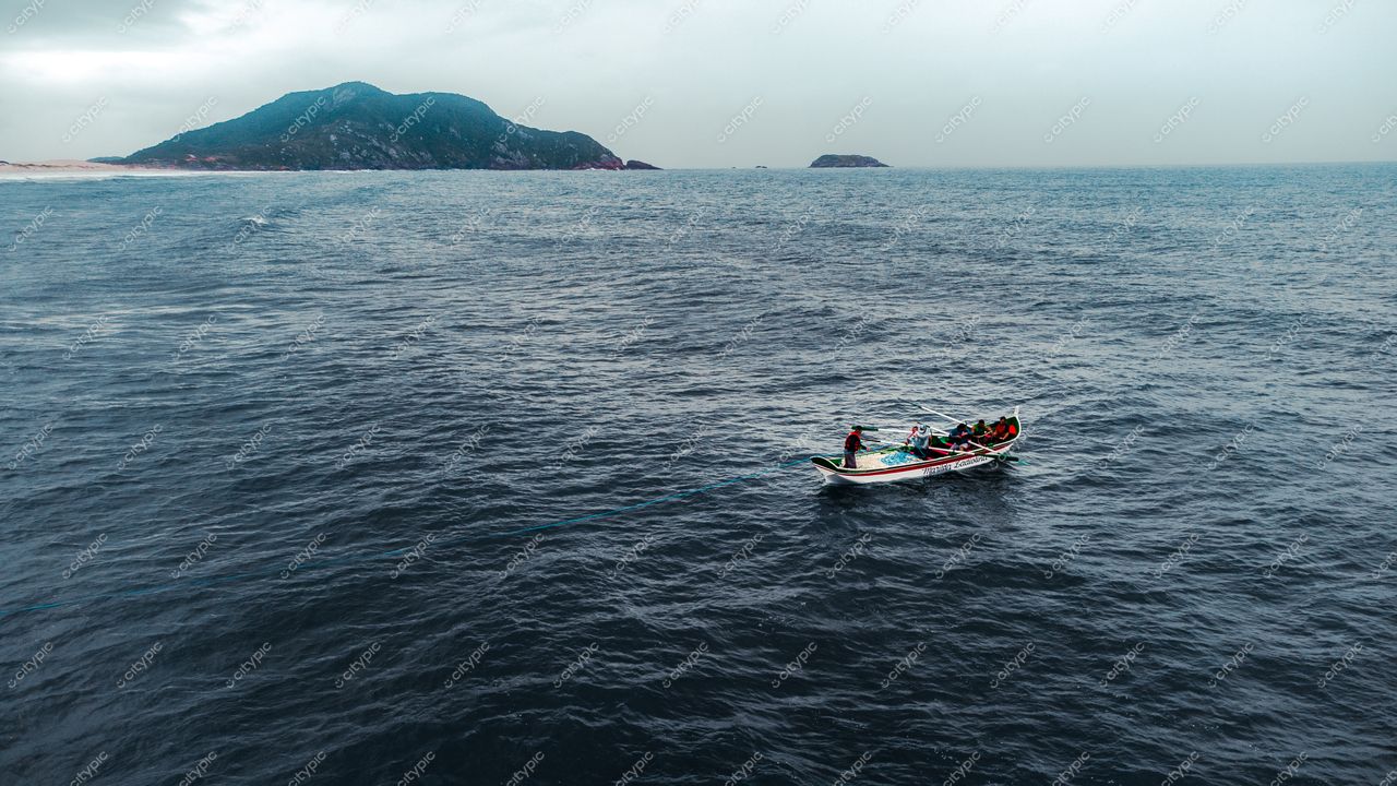Florianópolis, Santa Catarina barco de pesca à deriva em águas tranquilas com ilha montanhosa e céu nublado ao fundo