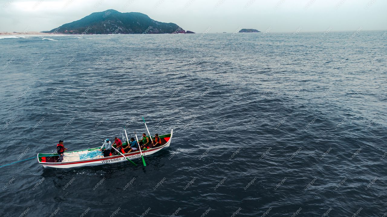 Florianópolis, Santa Catarina, barco de pesca tradicional em águas tranquilas com ilha montanhosa ao fundo em dia nublado