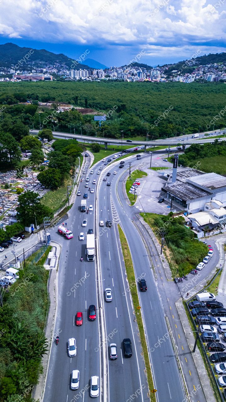 Hospital SOS Cárdio em Florianópolis com vista aérea do tráfego em dia nublado e vegetação ao redor da via principal