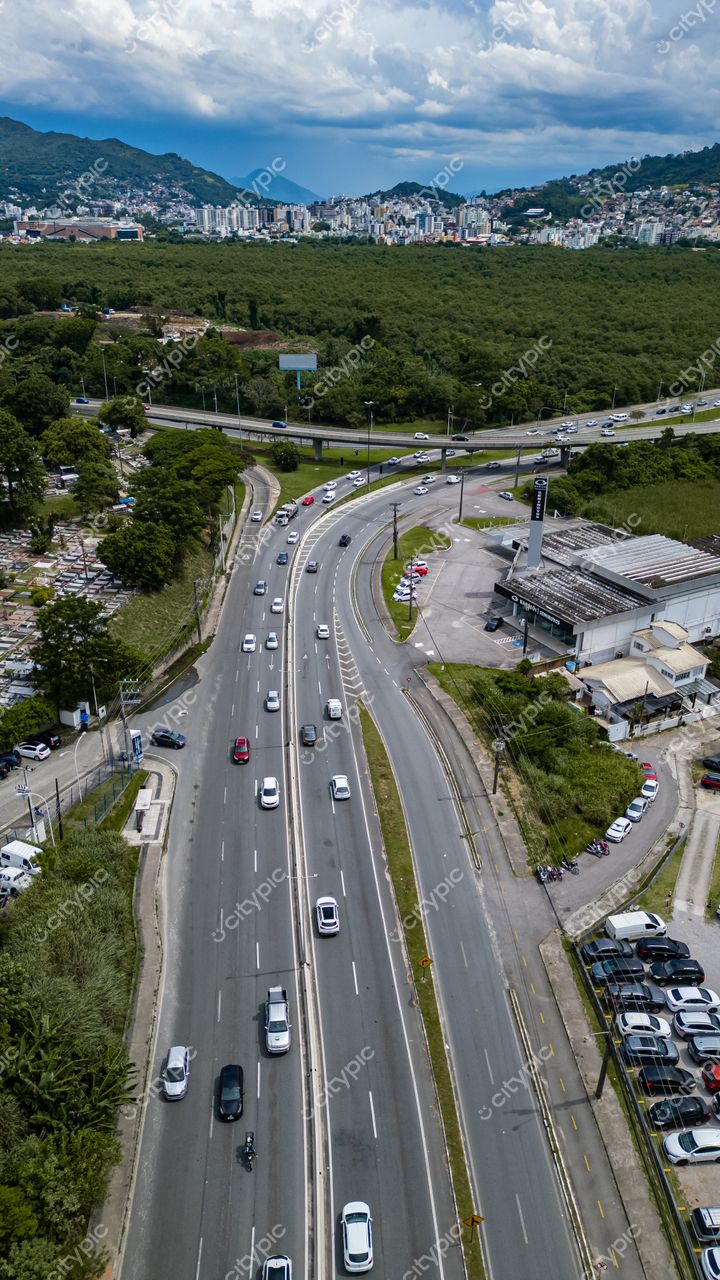 Hospital SOS Cárdio em Florianópolis vista aérea da interseção de rodovias com vegetação densa e céu parcialmente nublado