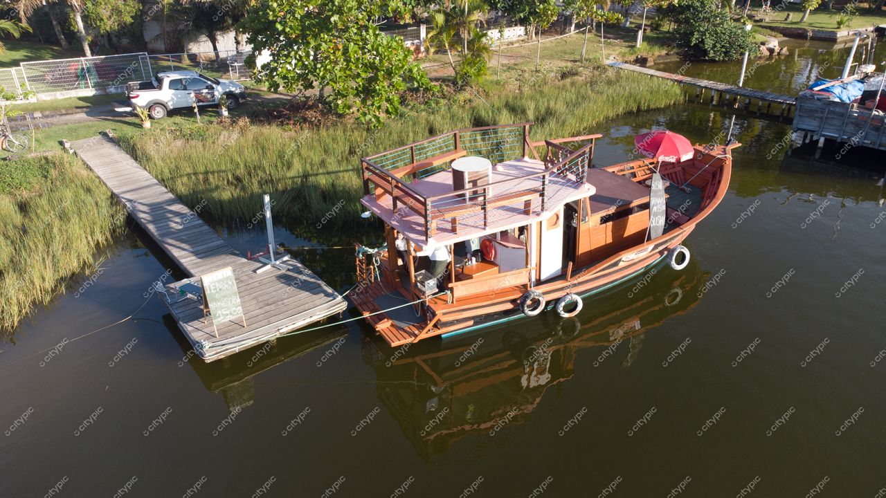 Florianópolis, Santa Catarina barco de madeira ancorado em canal tranquilo com ponte de madeira e vegetação ao fundo