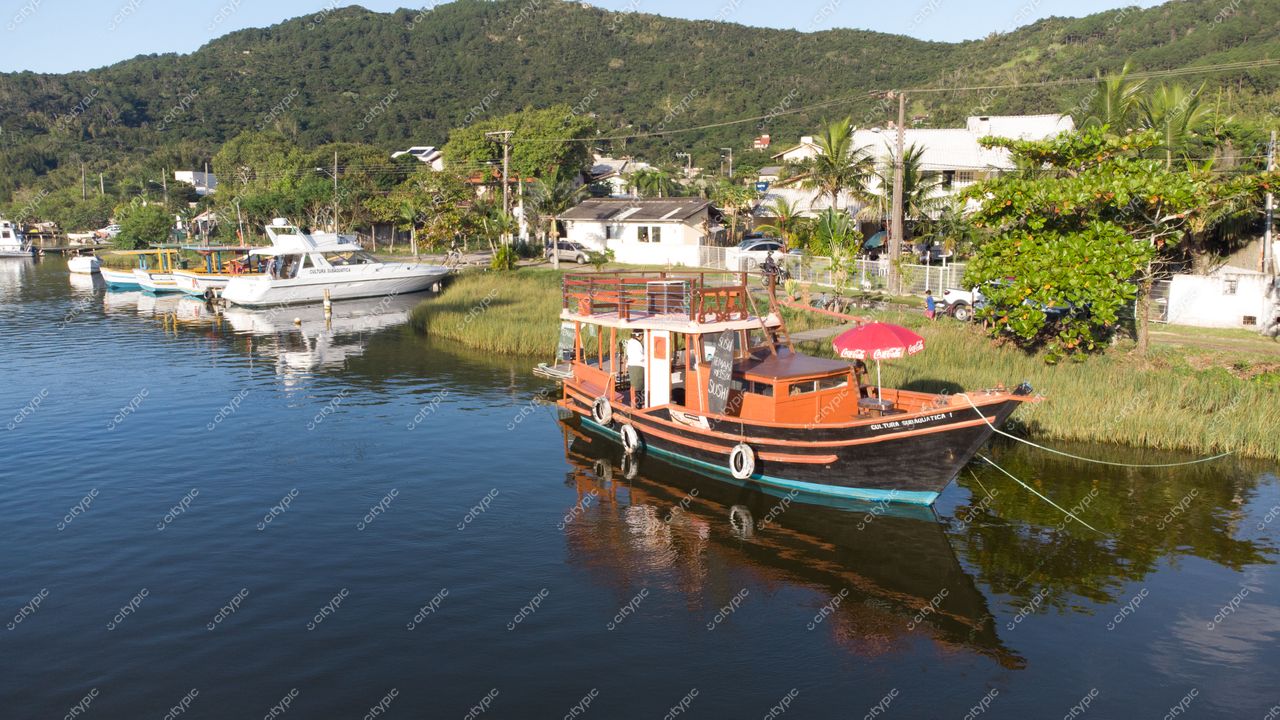 Florianópolis, Santa Catarina, ancoragem com barcos coloridos em canal tranquilo e vegetação ao redor em dia ensolarado