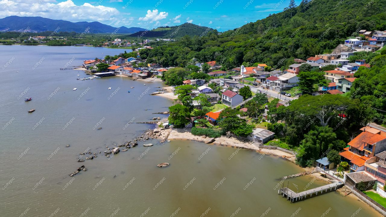 Ribeirão da Ilha em Florianópolis com casas coloridas, vegetação densa e montanhas ao fundo em luz natural diurna