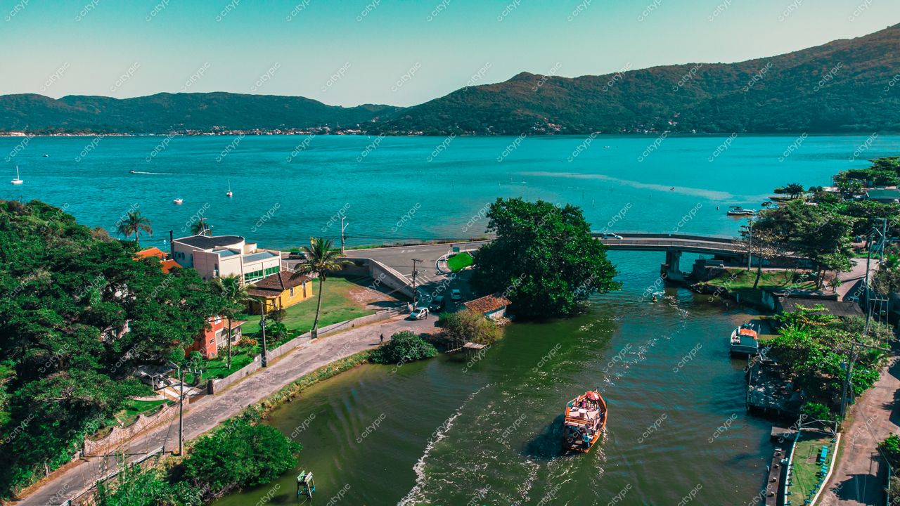 Florianópolis, Santa Catarina, vista panorâmica da baía com vegetação, residências coloridas e barco em dia ensolarado