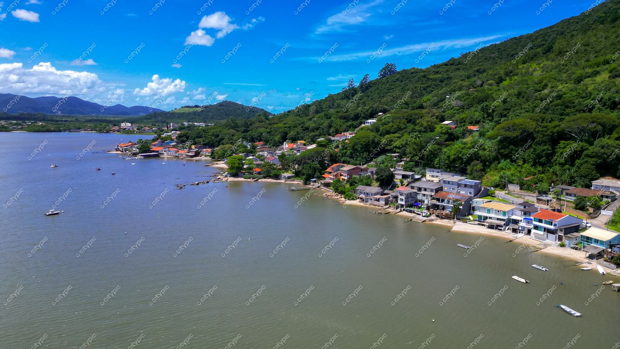 Ribeirão da Ilha em Florianópolis com vista aérea destacando casas residenciais, águas tranquilas e vegetação densa ao fundo