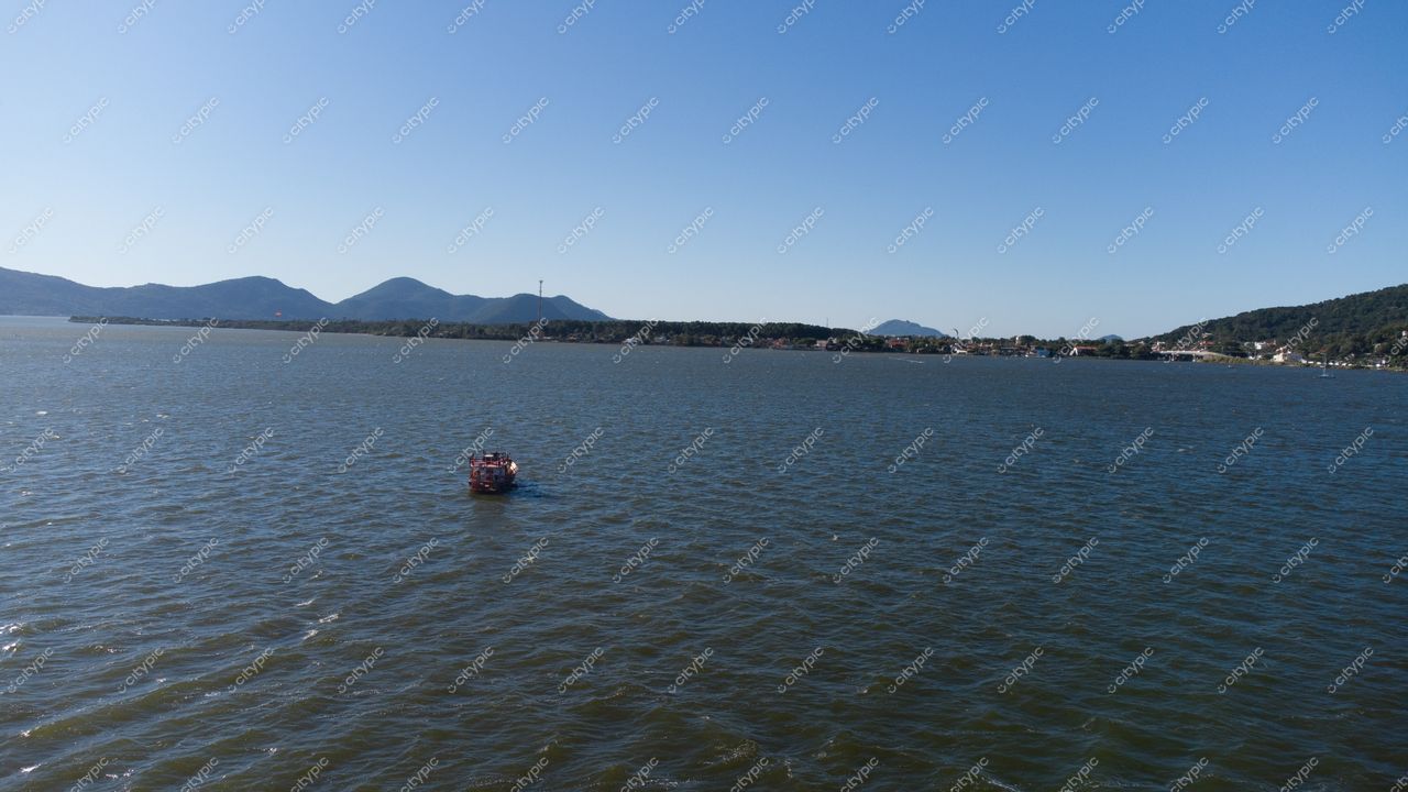 Florianópolis, Santa Catarina vista da lagoa com embarcação e montanhas sob céu azul claro durante o dia