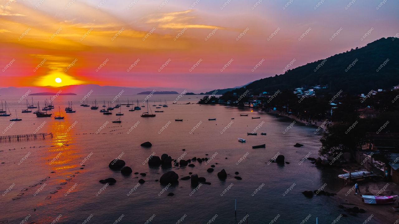 Florianópolis, Santa Catarina, pôr do sol na baía com reflexos laranja e rosa e embarcações ancoradas