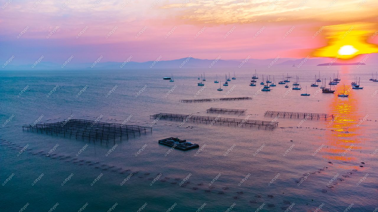 Florianópolis, Santa Catarina, pôr do sol com embarcações ancoradas e estruturas aquáticas em mar tranquilo e montanhas ao fundo