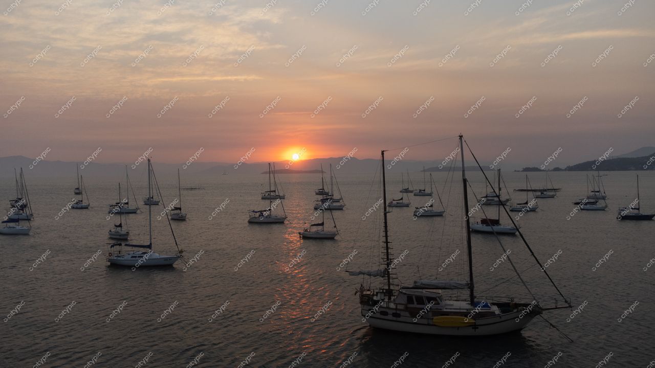 Florianópolis, Santa Catarina, pôr do sol sereno com embarcações ancoradas e montanhas ao fundo em tons suaves
