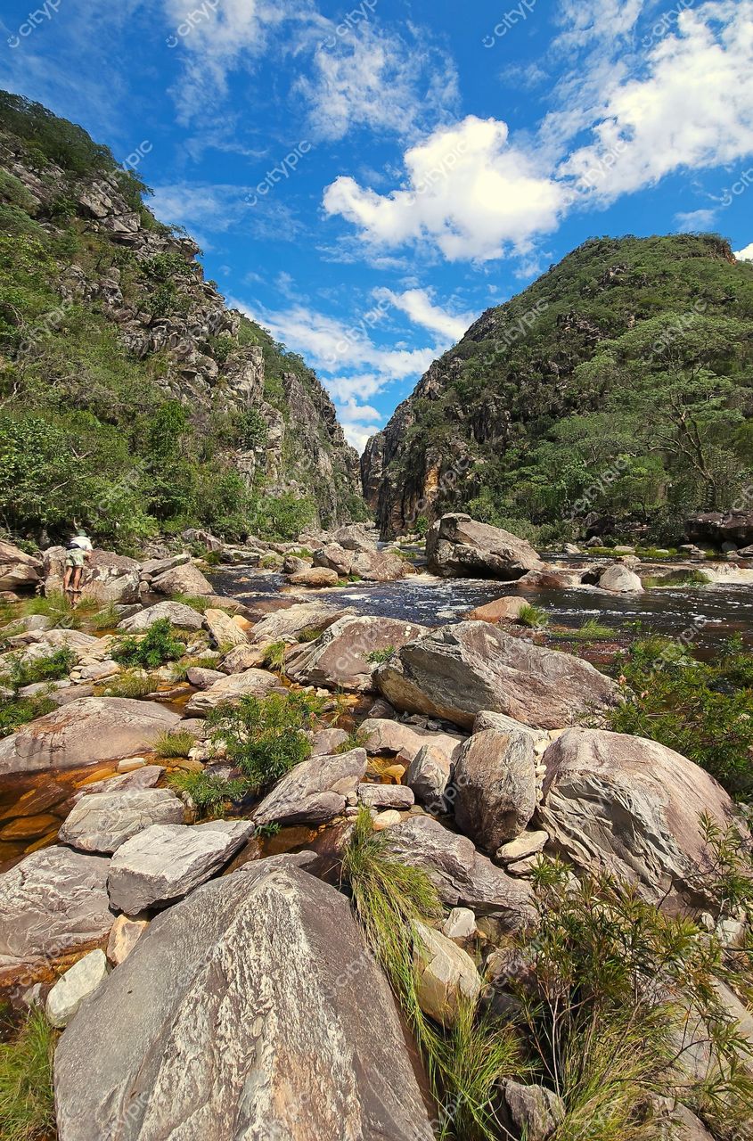 Santana do Riacho, Minas Gerais, paisagem com formações rochosas e riacho entre vegetação densa sob céu azul