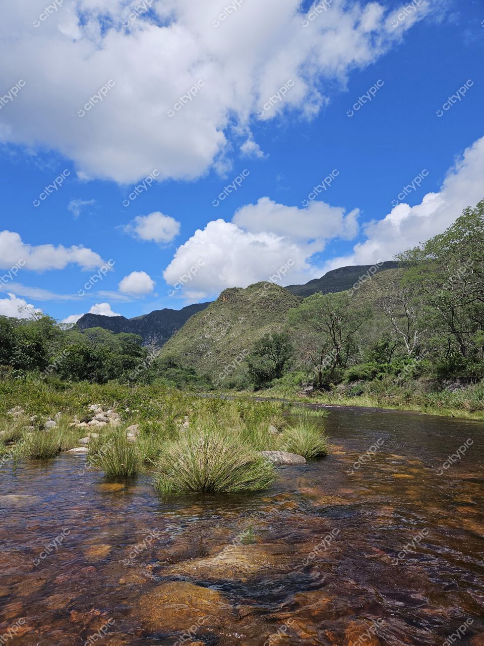 Santana do Riacho, Minas Gerais, rio de águas cristalinas refletindo céu azul e montanhas verdes ao fundo