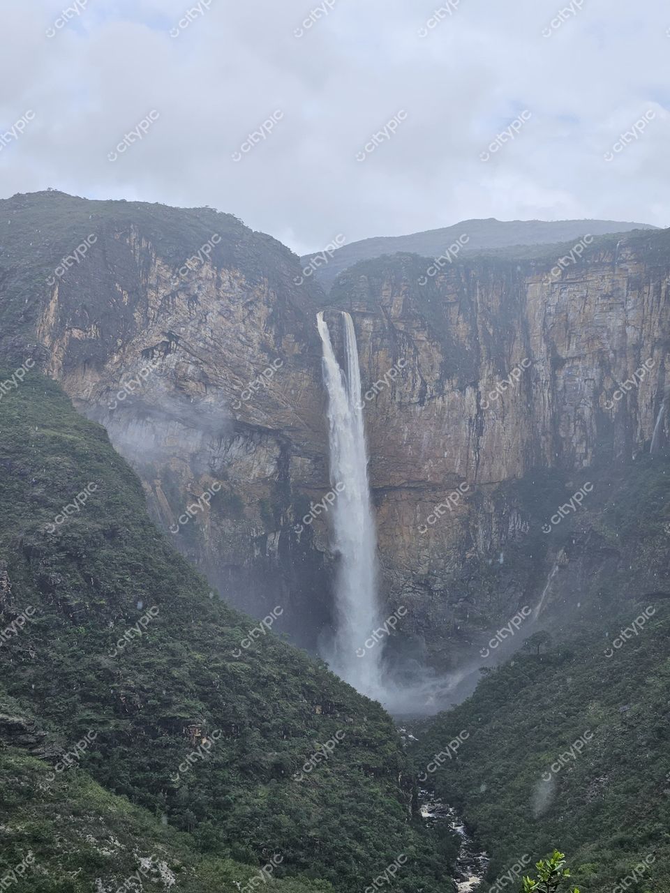 Conceição do Mato Dentro, Minas Gerais, cachoeira em vale profundo com vegetação densa e céu nublado em clima úmido