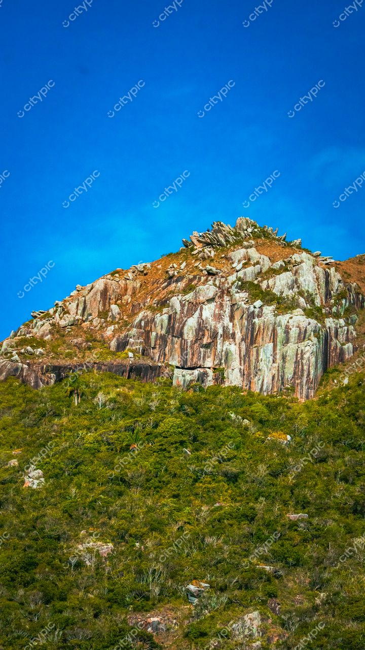 Lagoinha do Leste em Florianópolis com relevo rochoso cinza e laranja sob céu azul claro durante o dia