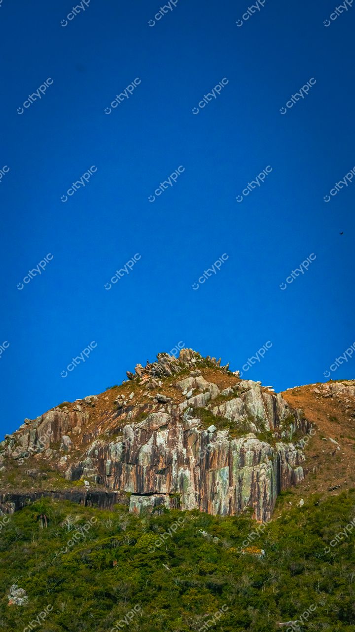 Lagoinha do Leste em Florianópolis com rocha imponente e vegetação esparsa sob céu azul durante o dia
