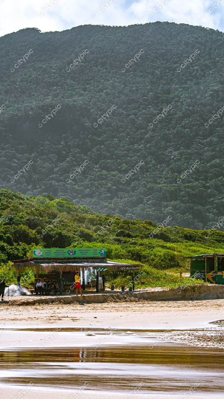 Lagoinha do Leste em Florianópolis com quiosque de palha e relevo montanhoso sob iluminação natural em dia claro